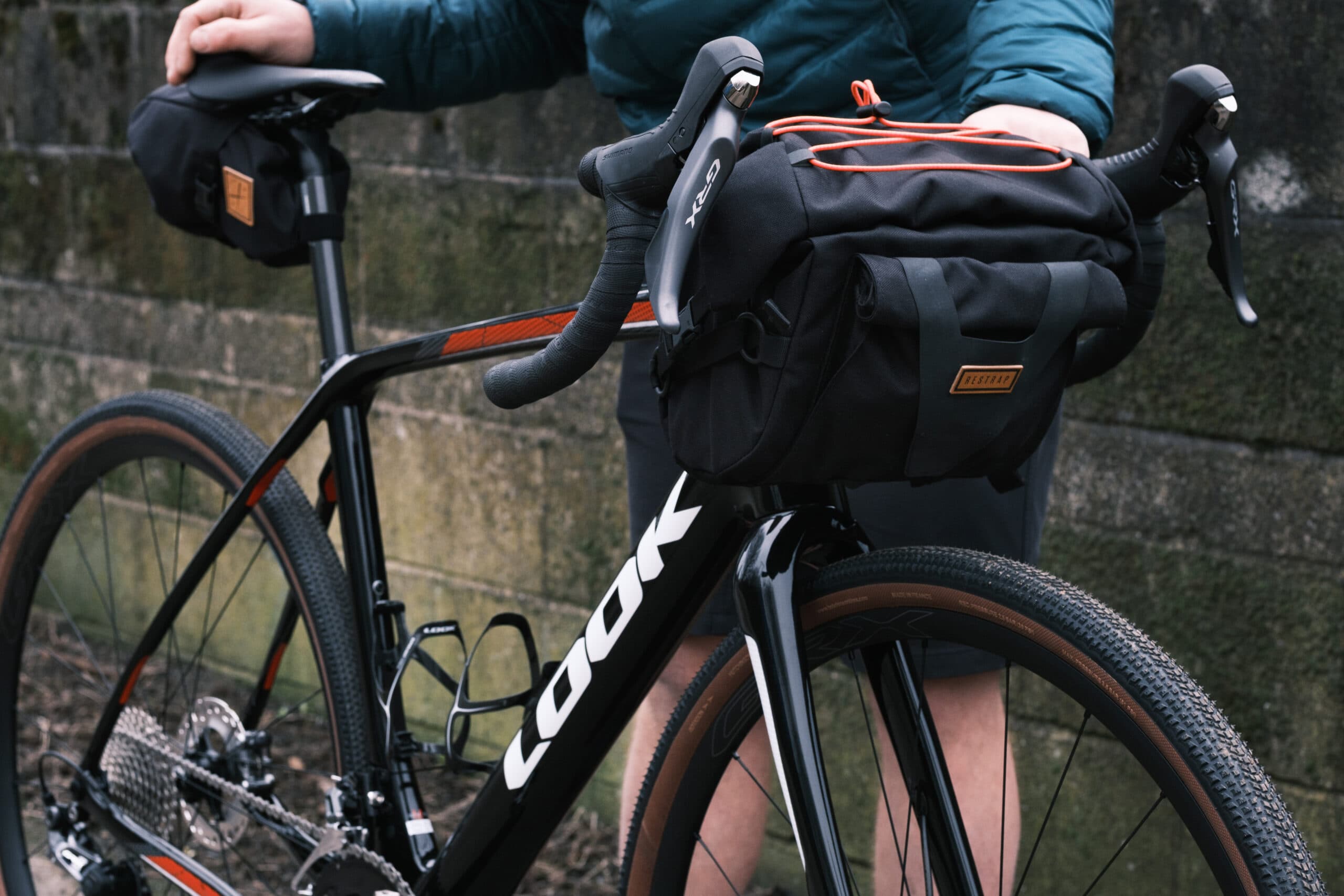 Gravelfiets met Restrap stuur- en zadeltassen bij een stenen muur